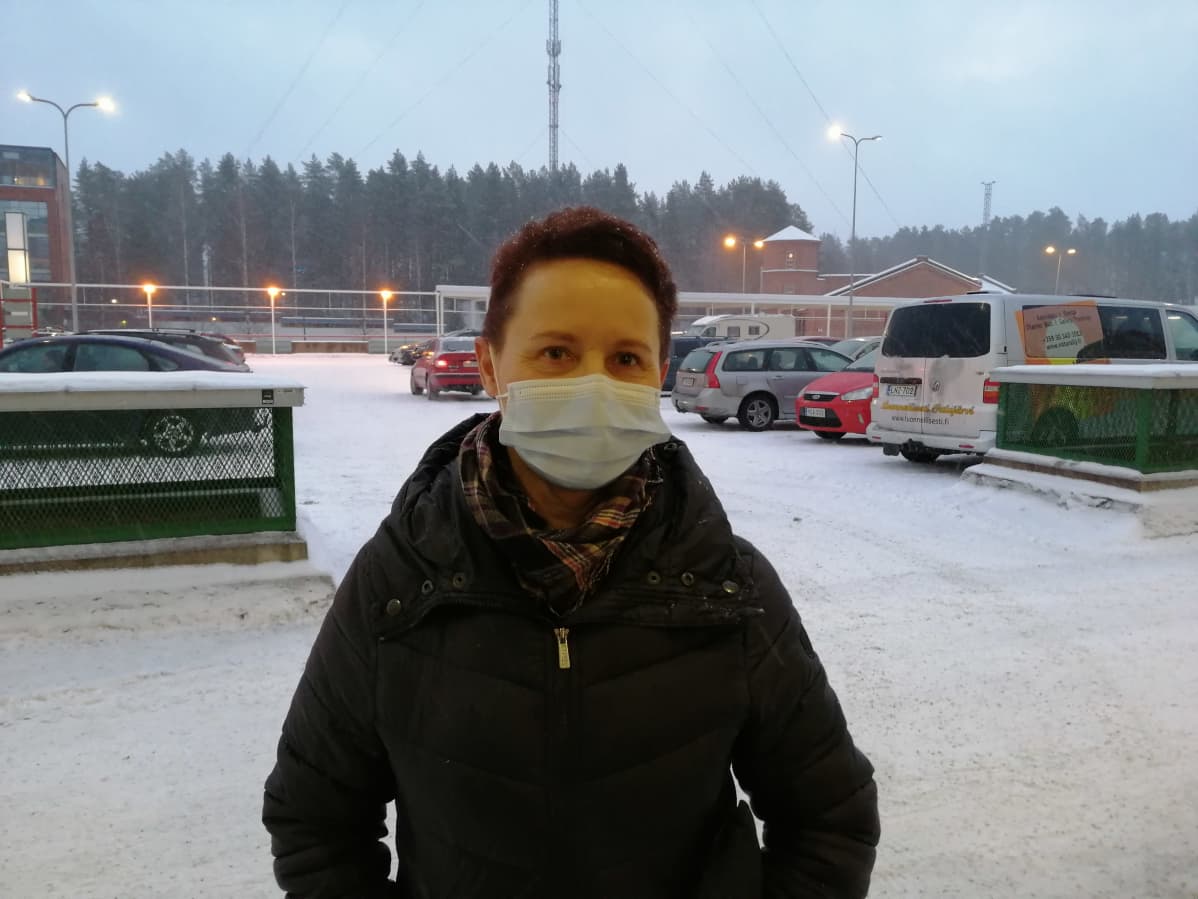 Nainen maski kasvoillaan parkkipaikalla.