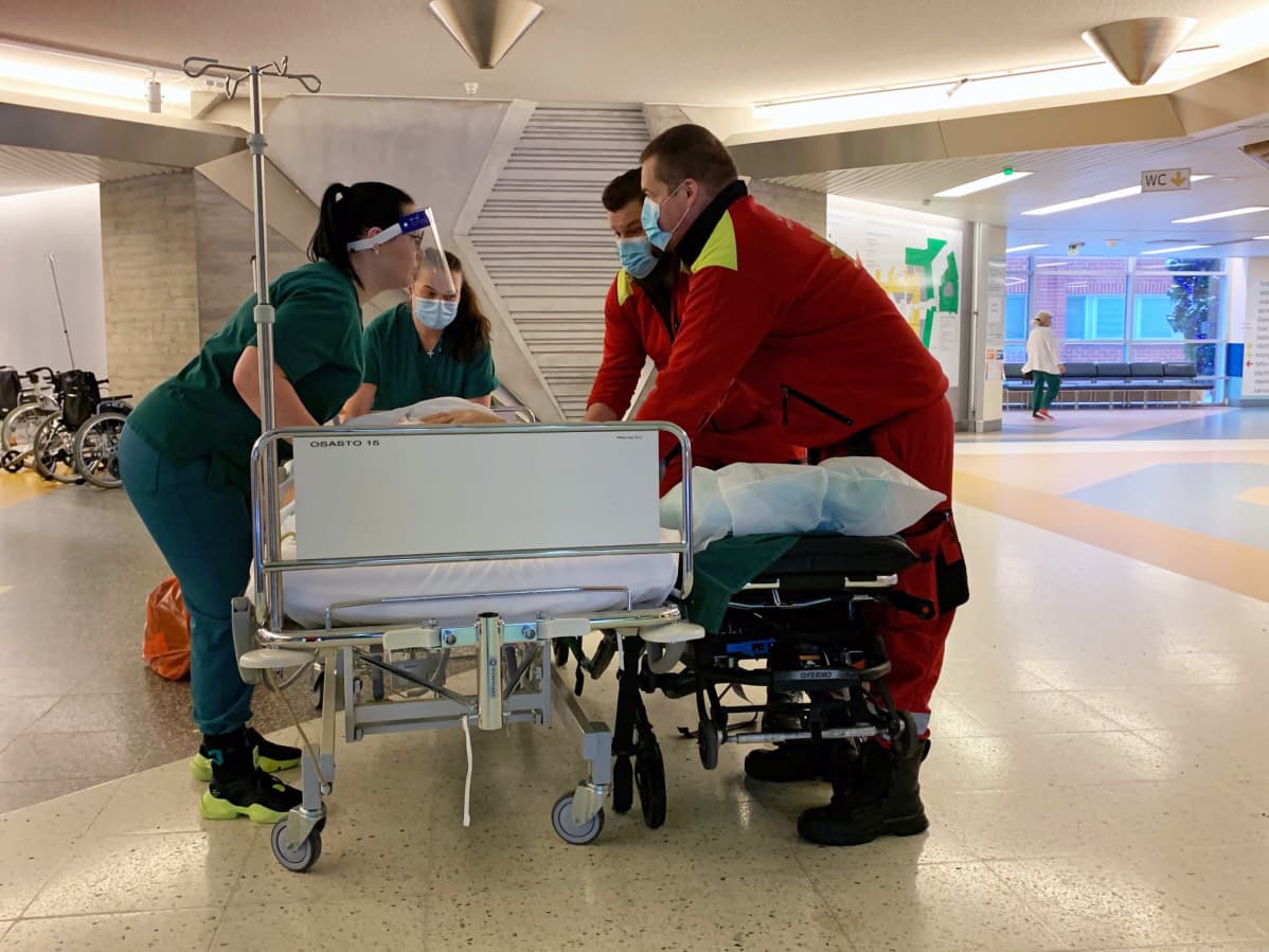 Henkilökunta kuljettaa potilasta sairaalan käytävällä.