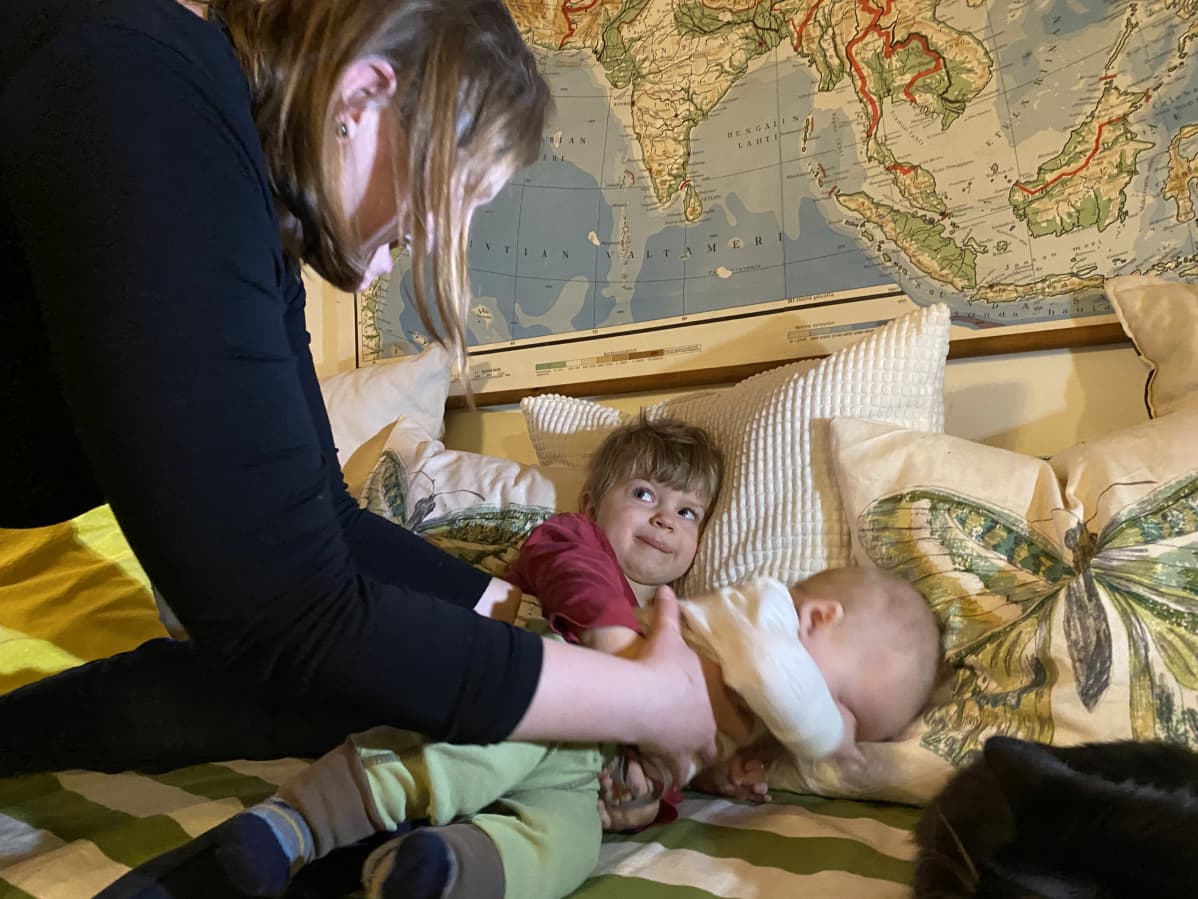 Iippo ja Aatos sohvalla. Anne nostaa Aatosta syliin. Iippo katsoo Annea.