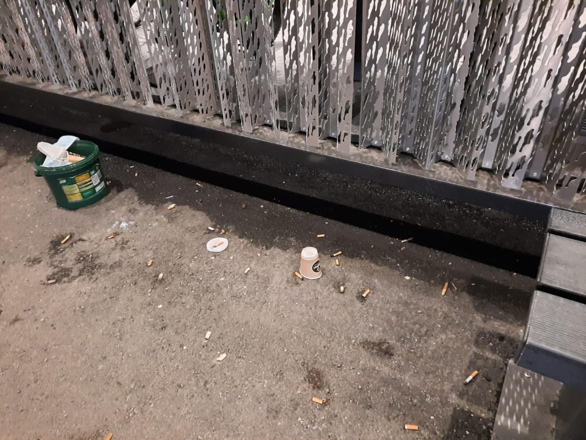 Roskia ja tupakantumppeja sairaalan seinustalla.