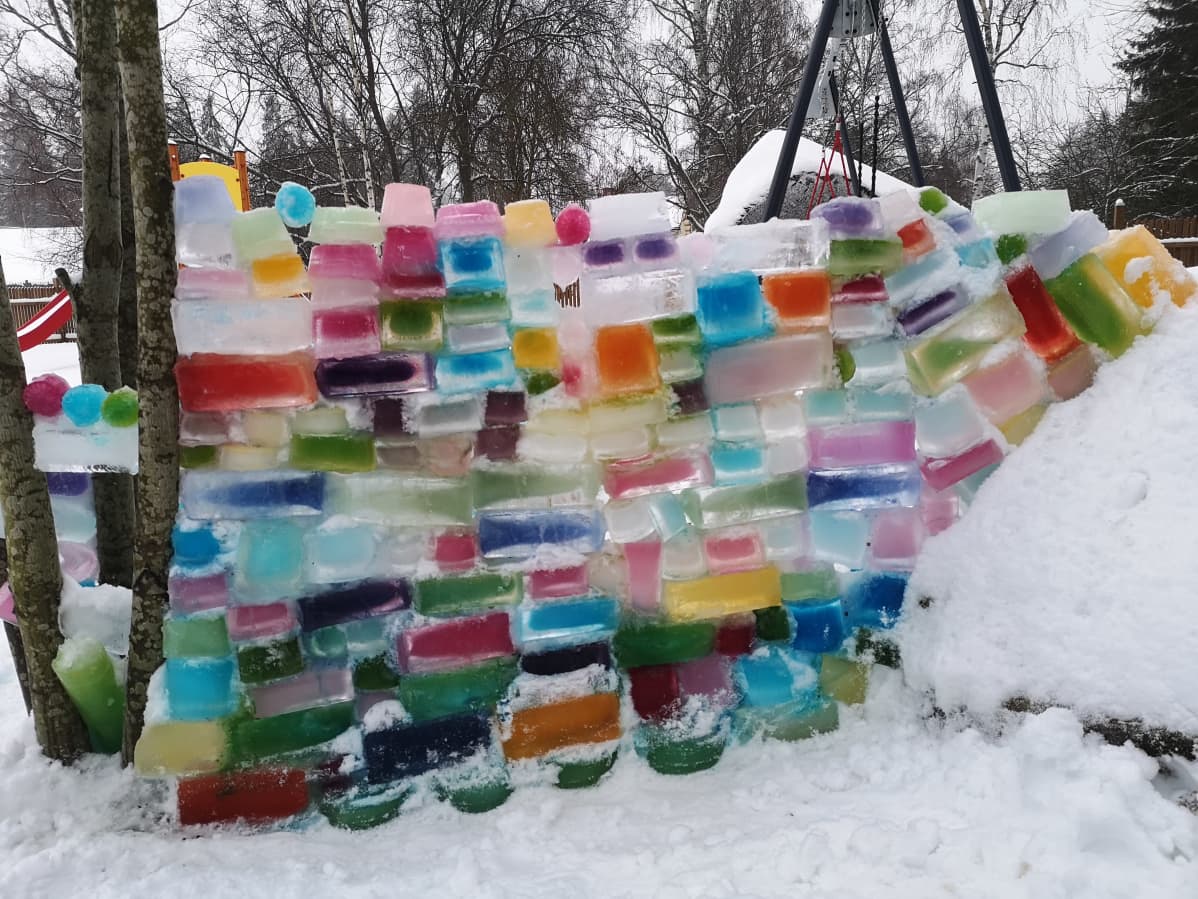 Värikäs jääpaloista koottu muuri puun ja kiven välissä