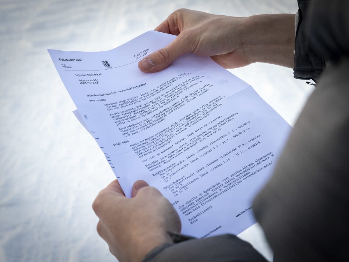 Korkeakouluopiskelijan terveydenhoitomaksun maksumuistutuskirje opiskelijan kädessä.