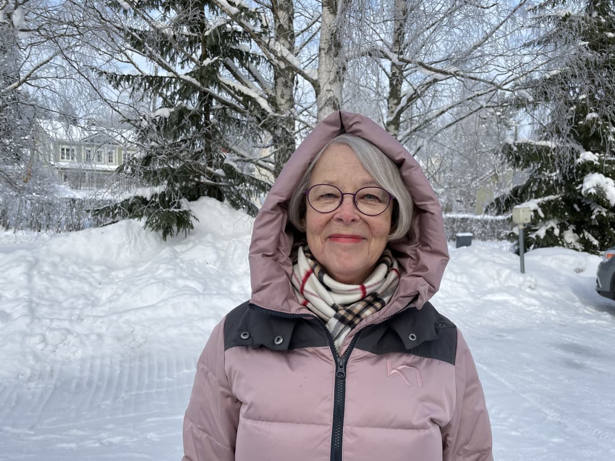 Harmaatukkainen nainen hymyilee.