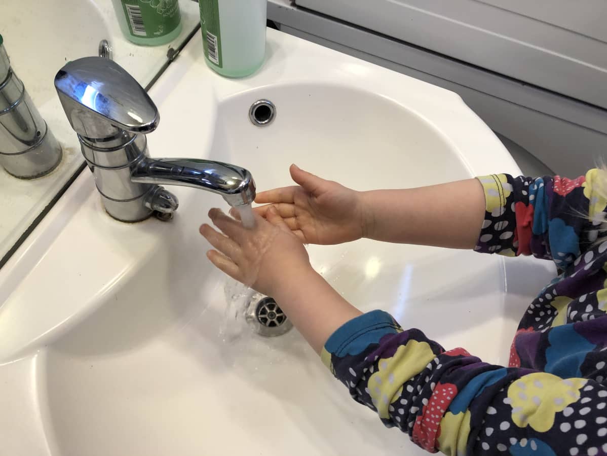Lapsi pesee käsiä vesihanan alla.
