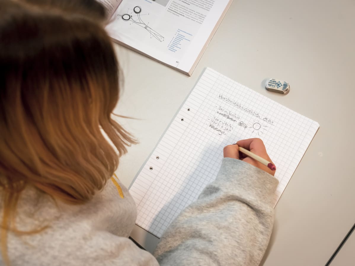 Oppilas kirjoittaa vihkoon.