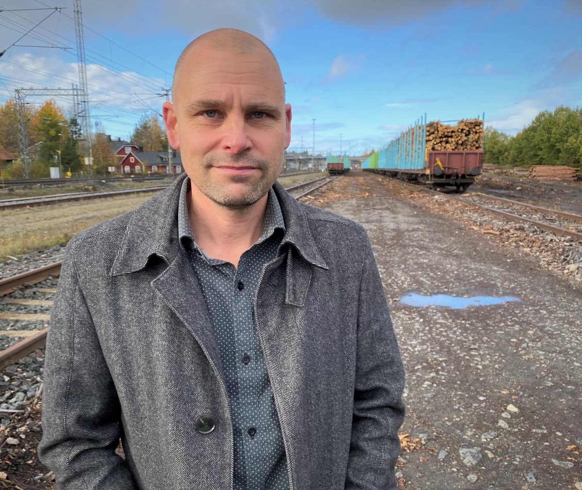 Mies seioo ratapihalla, takana pitkä juna