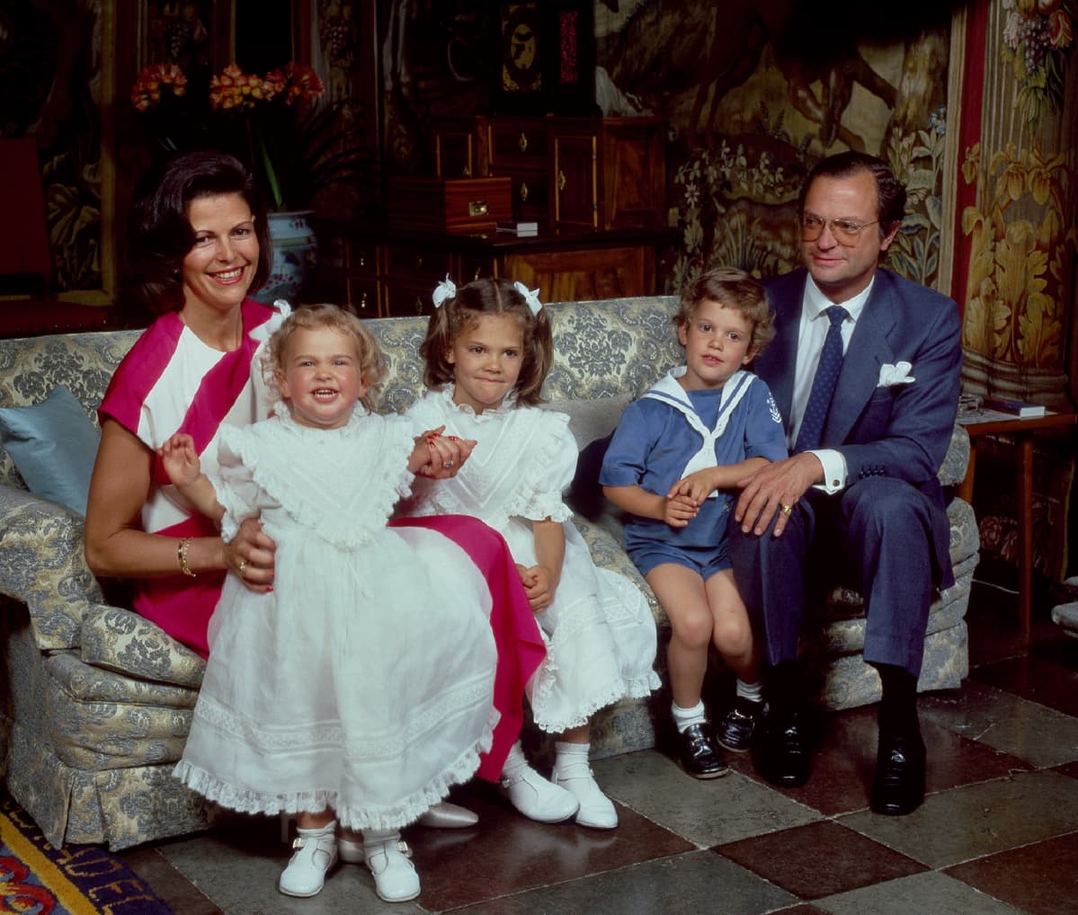 Madeleine istuu kuningatar Sylvia sylissä, vieresssa Victoria (kesk.), Carl Philip ja kuningas Kaarle Kustaa (oilk.)