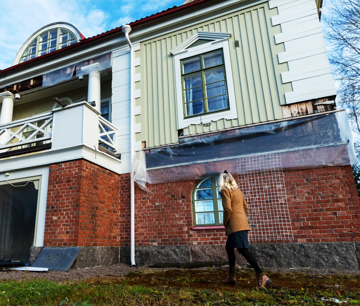 Terttu Aalto kävelee Villa Idan pihalla, katsoo huvilaa kohti.