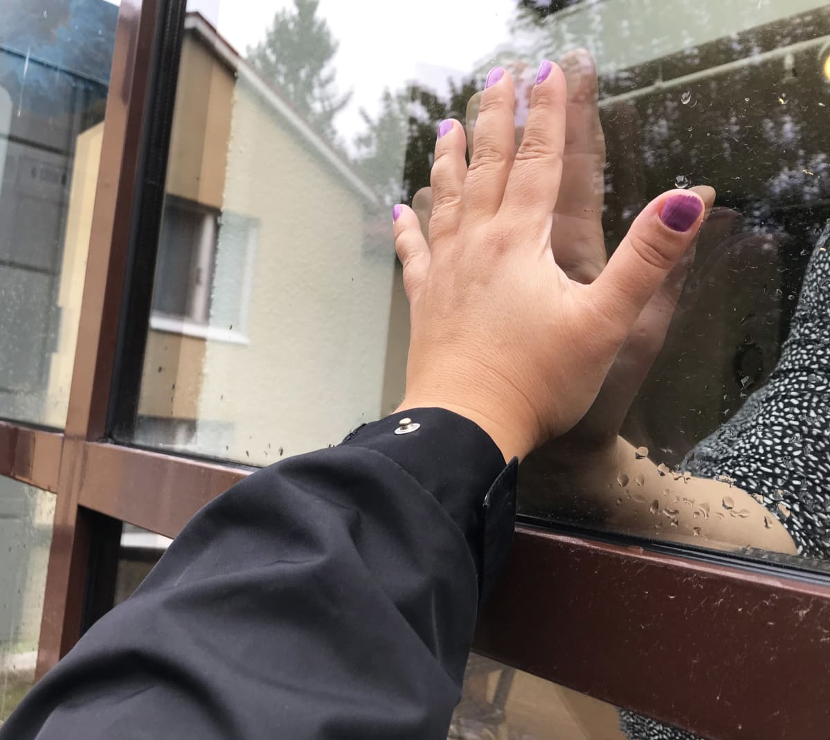 Kädet palvelutalon ikkunassa.