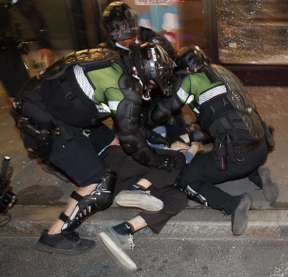 Kaksi poliisia pidättämässä ihmistä.