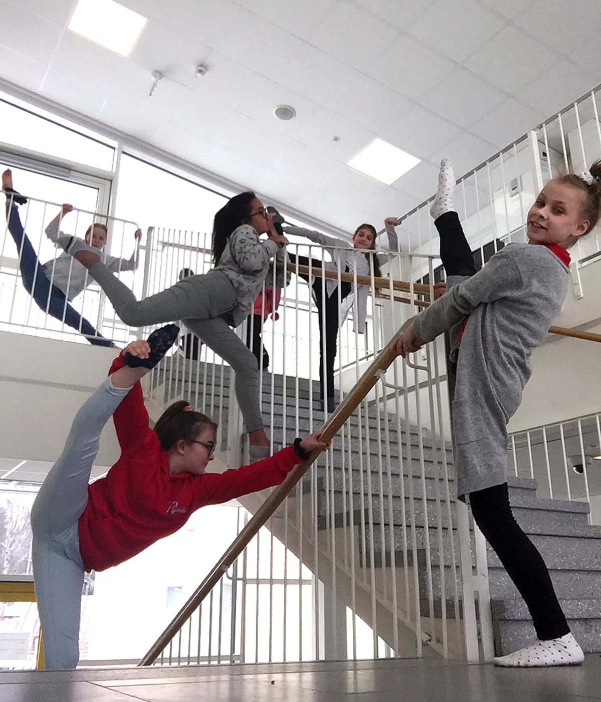 Joukko lapsia venyttelee portaissa.