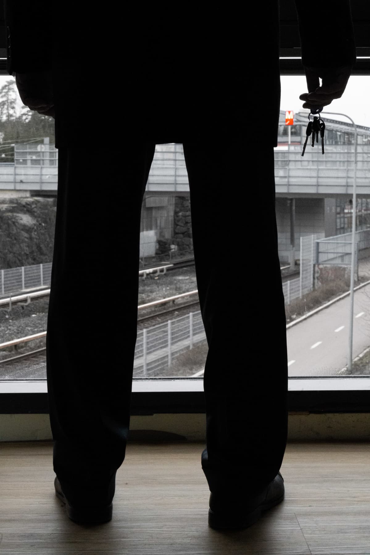 Silhuettina ikkunaa vasten seisova mies, jolla avainnippu kädessä.