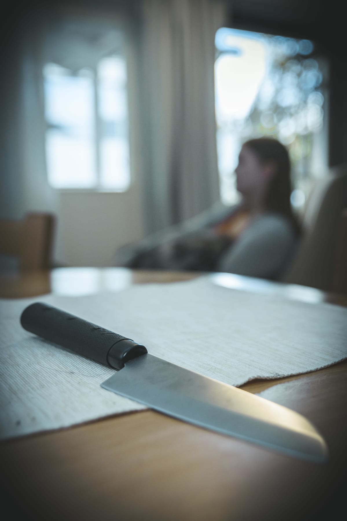 Petra Suonperä koira sylissään katsoo sohvalla kauhuelokuvaa. Etualalla puukko.