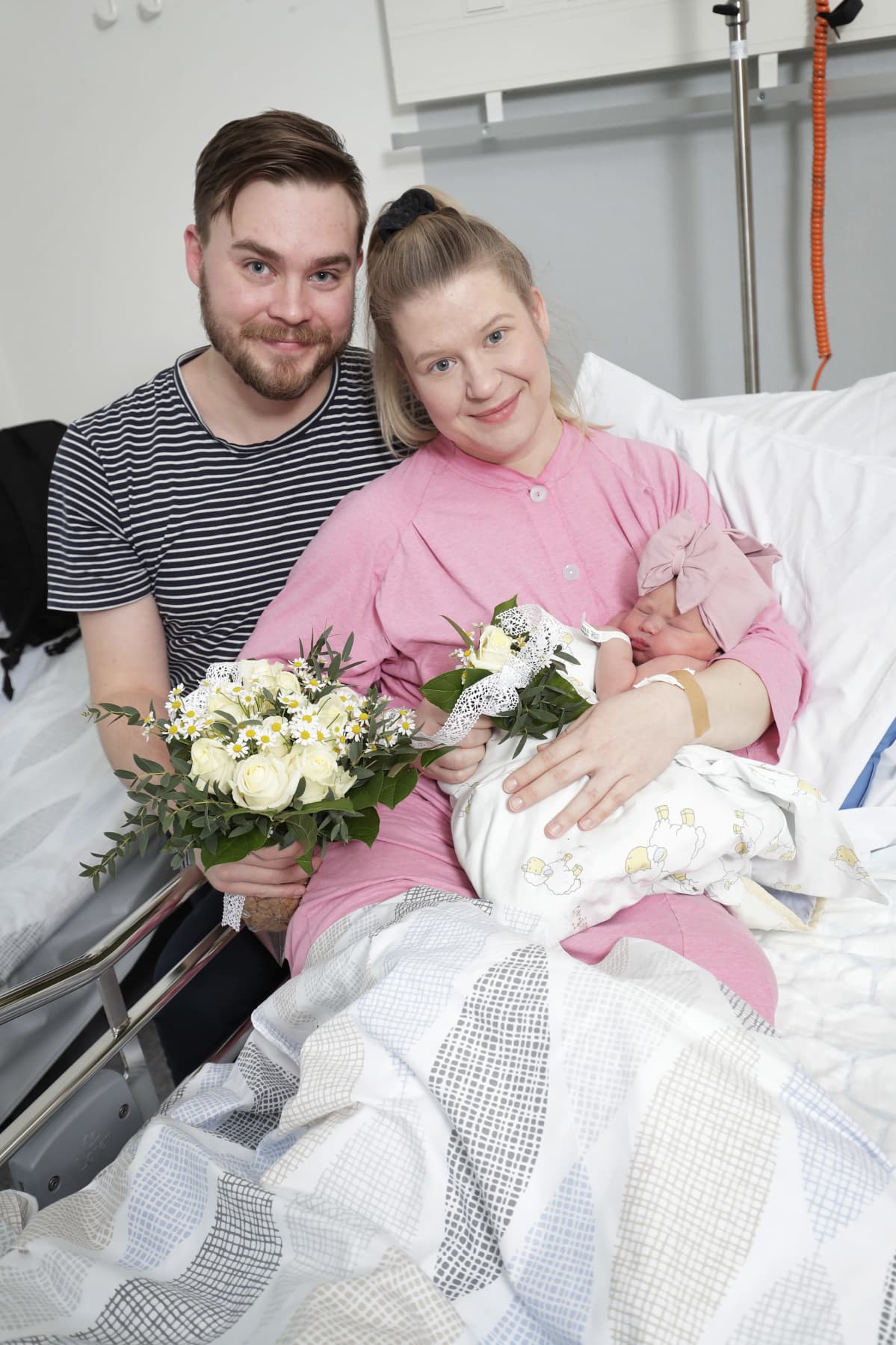 Tuoreet vanhemmat vastasyntynyt vauva sylissään.