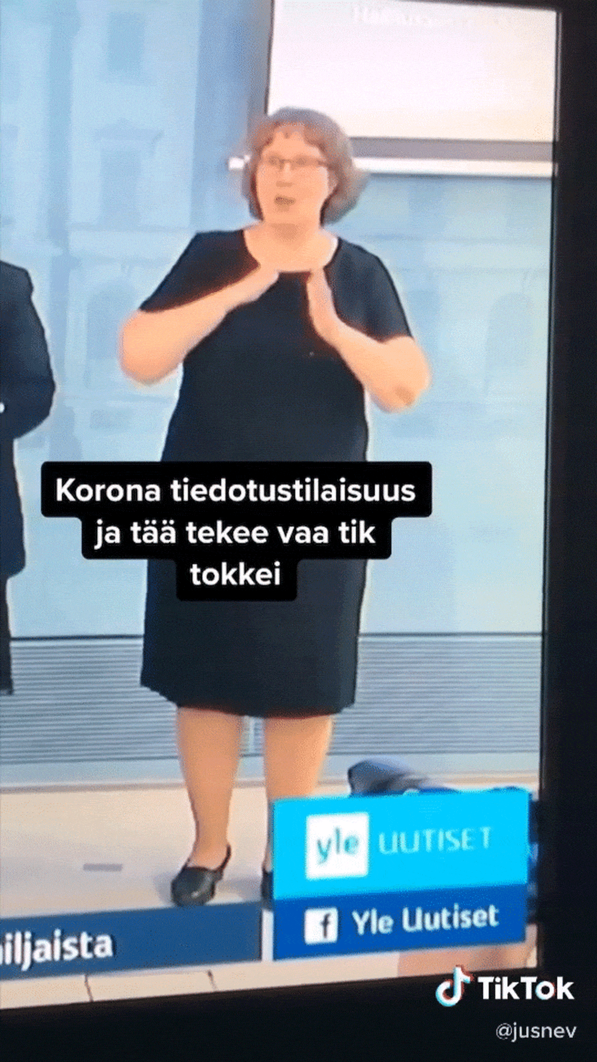 Videopätkä TikTokista, jossa viittomakielen tulkki Outi Huusko tulkkaa tiedotustilaisuutta.