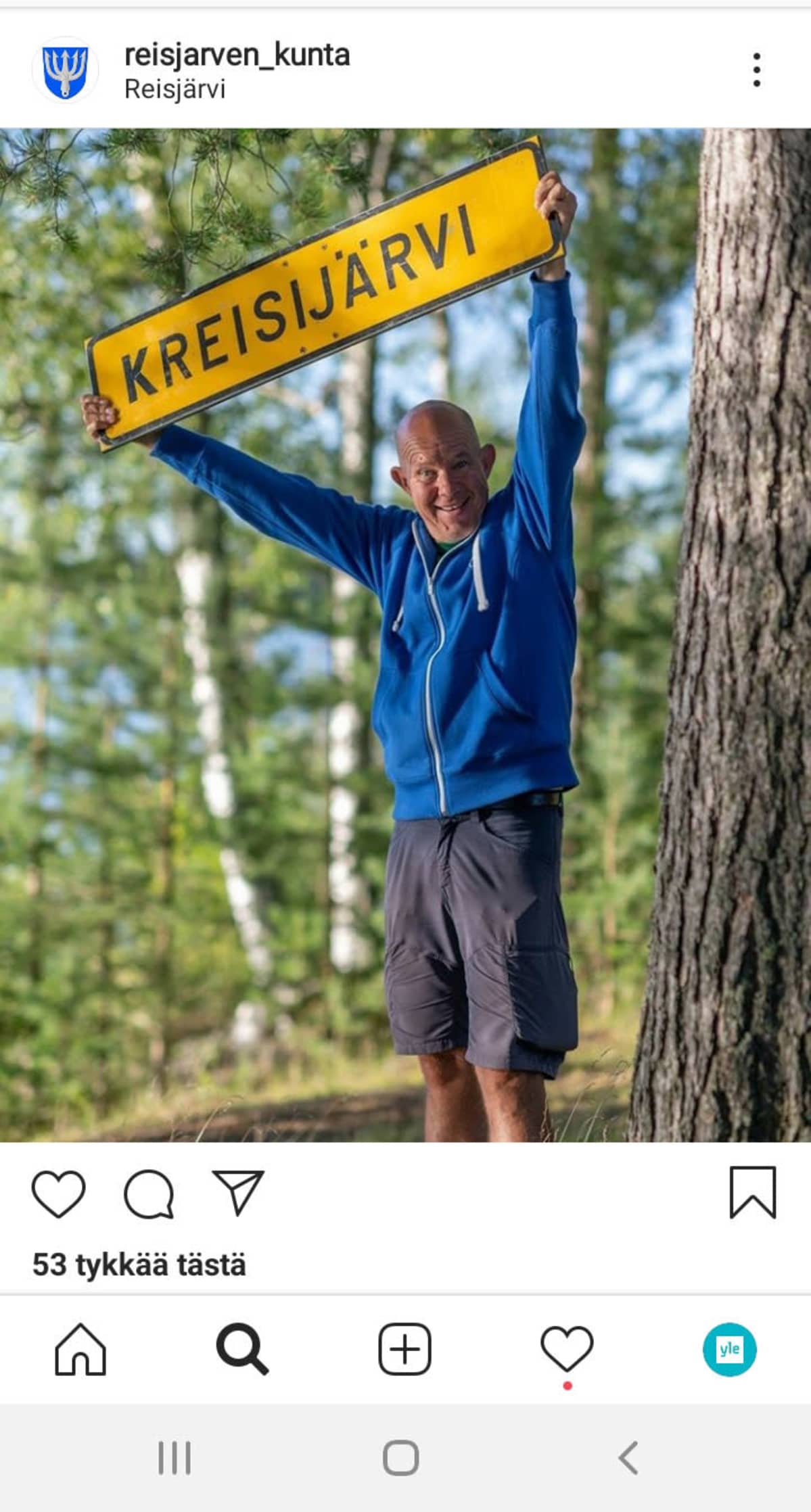 Kuvakaappaus Reisjärven Instagram-sivulta. Kaj Kunnas pitää kädessään Kreisijärvi-kylttiä.