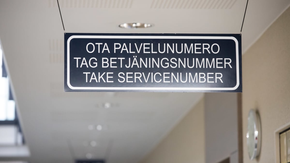 Kuvassa katosta roikkuva kyltti Kokkolan poliisiasemalla. Kyltissä lukee ota palvelunumero