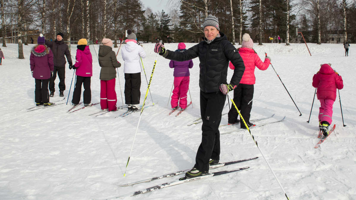 Opettaja ja koululaisia hiihtämässä