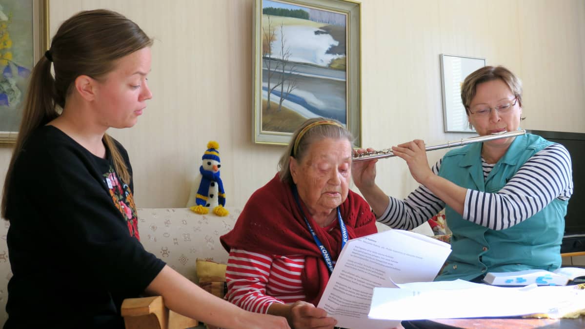 Sairaalamuusikko Iida-Maria Uljas ja lähihoitaja Sari Perätalo kotihoidon käynnillä Aune Kuusenhakon luona.