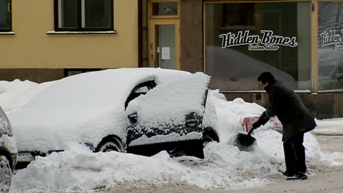 Mies kaivaa autoa kinoksesta