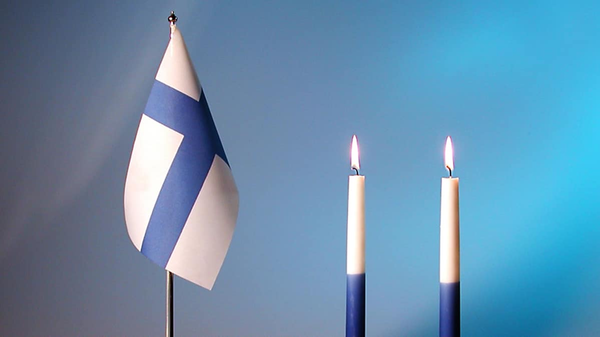 Suomen lippu ja kaksi kynttilää.
