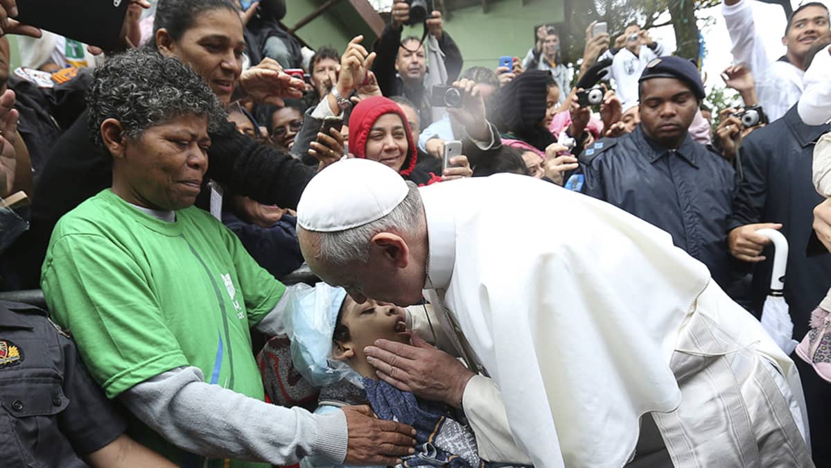 Paavi Franciscus siunaa lapsen vieraillessaan Varginhan favelassa Rio de Janeirossa.