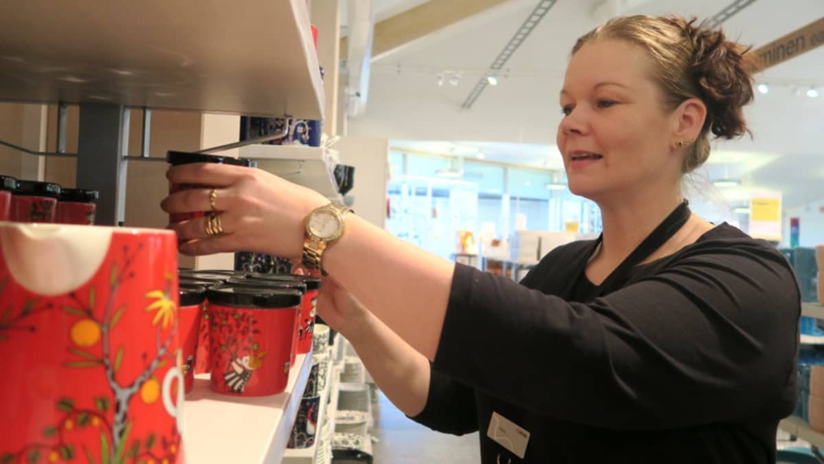 Myyjä asettelee muumituotteita hyllyyn