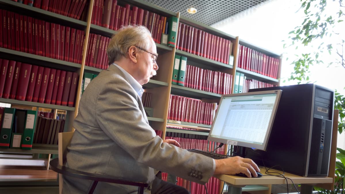 Ilkka Lehtinen asettui kuvattavaksi Tilastokeskuksen kirjastoon.