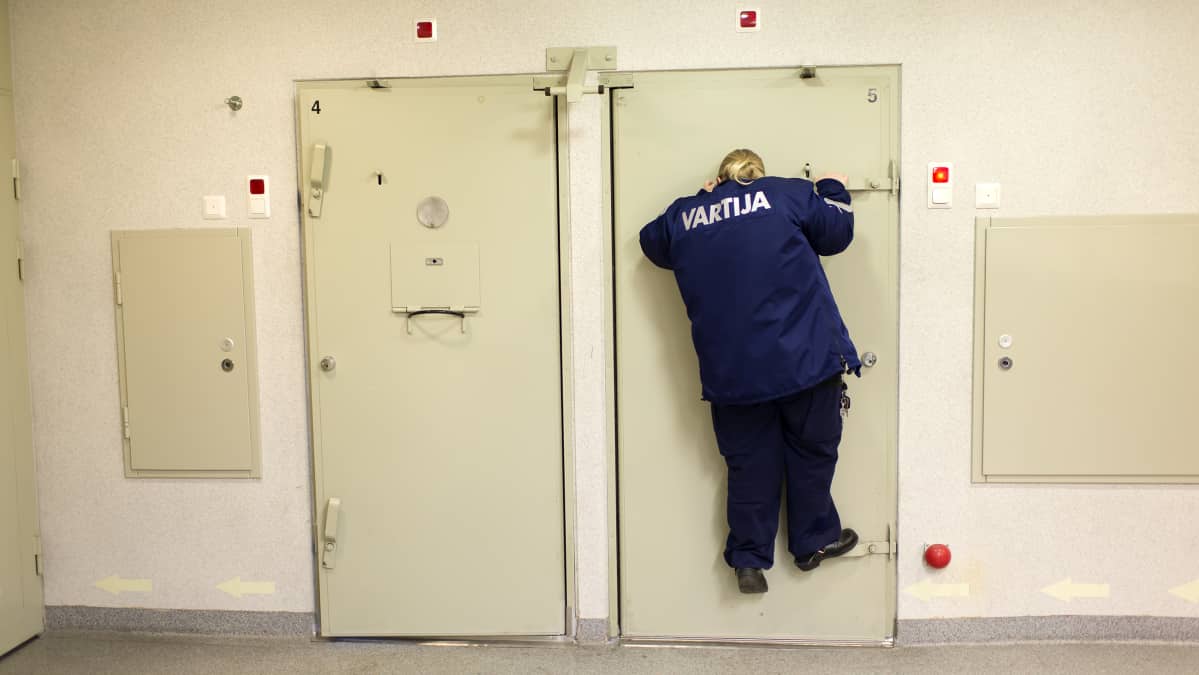 Kokkolan poliisivankilan vartija Ulpu Keränen kurkkaa selliin ovisilmästä.