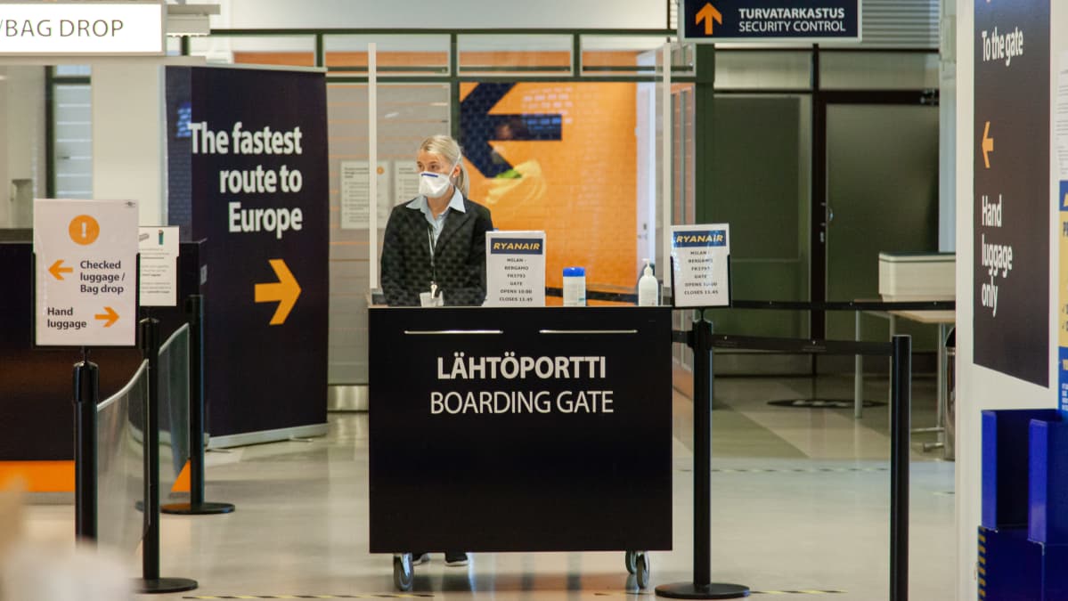 Lappeenrannan lentoaseman lähtöportti koronaviruksen aikaan. Työntekijällä hengityssuojaimet ja kumihanskat.