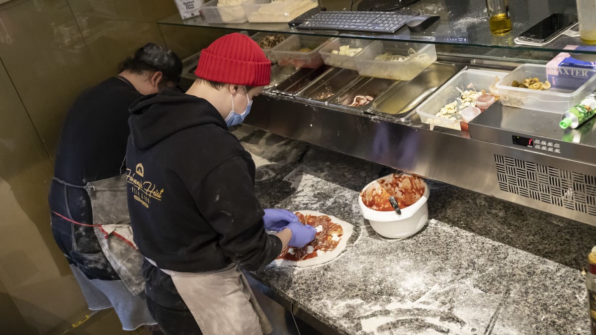 Kaksi ihmistä tekemässä pizzaa.
