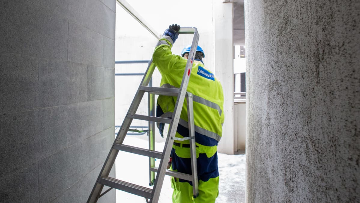 Enersense-yhtiön työntekijä kantaa tikapuita. (Entinen empower)