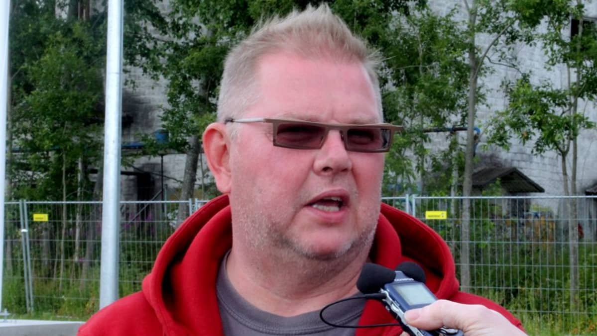 Lyhyttukkainen silmälasipäinen mies kommentoi mikrofoniin