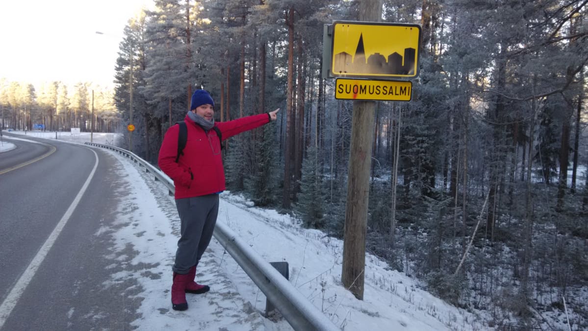 Raul Valiente osoittaa Suomussalmen taajama -kylttiä