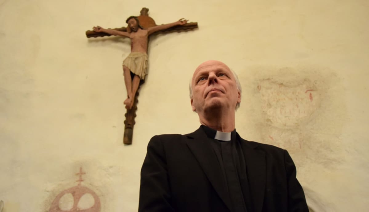 Pappi Reijo Sillanpää Vanajan kirkossa, taustalla krusifiksi