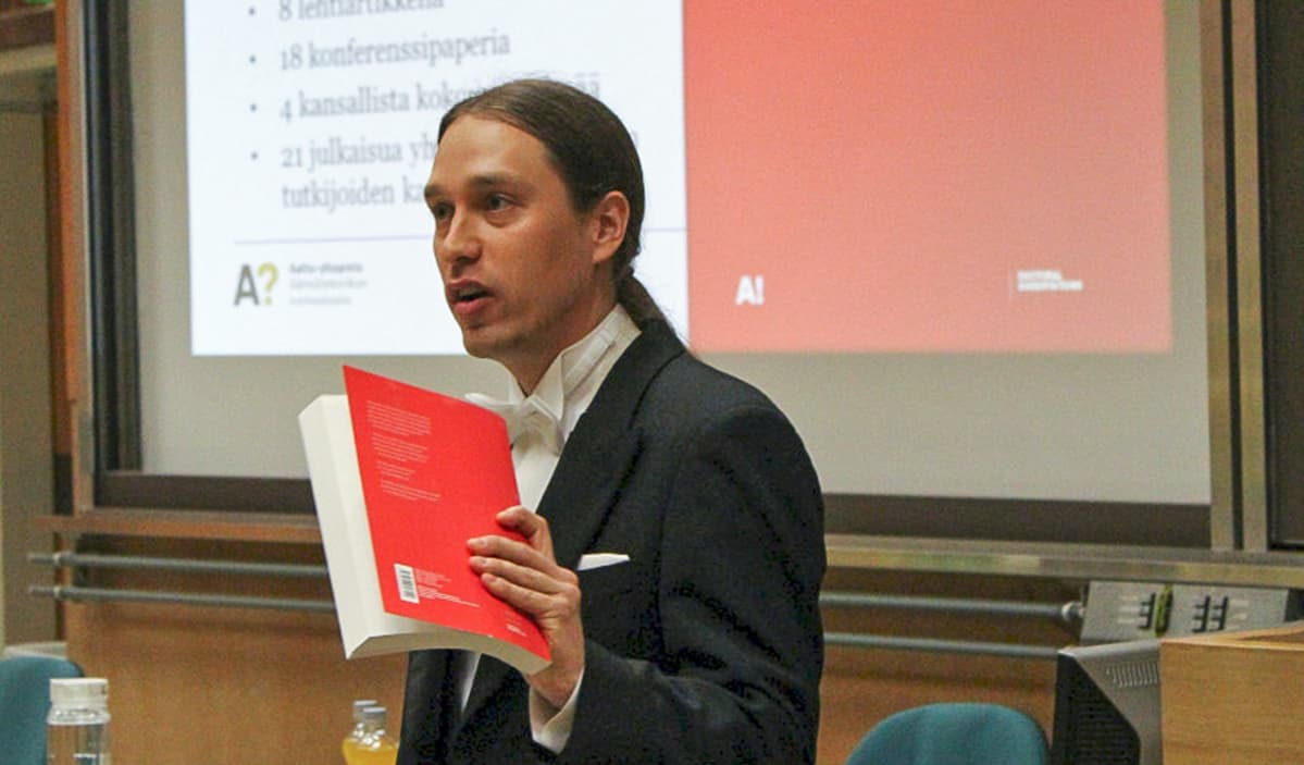 Taneli Riihonen puhuu kirja kädessään.