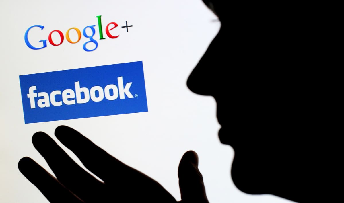 Ihmishahmo silhuettina näytön edessä, näytöllä Googlena ja Facebookin logot.