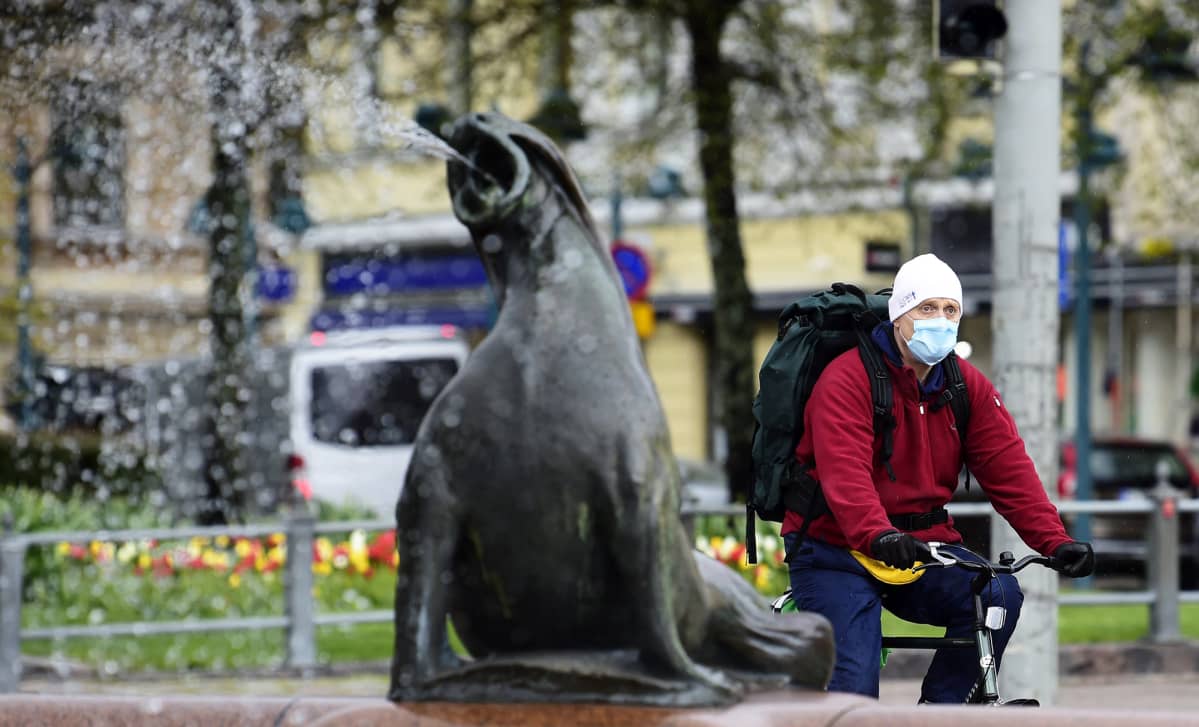 Hengityssuojainta käyttävä pyöräilijä ohittaa Havis Amandan suihkulähteen Helsingissä.