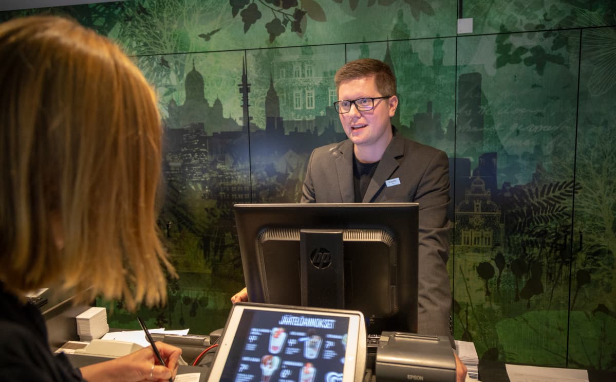 Vastaanottovirkailija työskentelee hotellin aulassa.