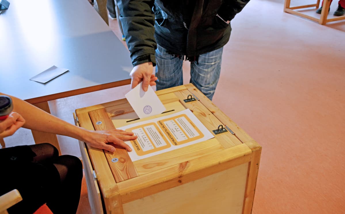Kuvassa henkilö laittaa äänestyslipukkeen uurnaan.