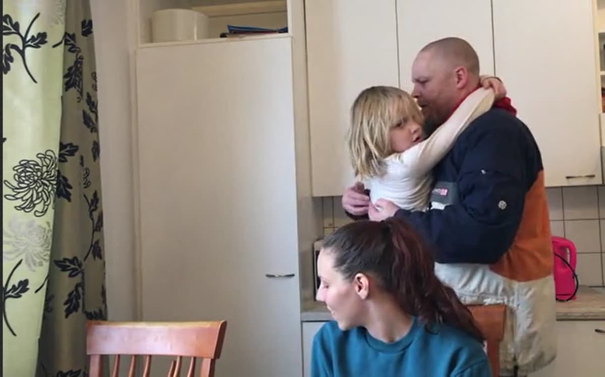 lapsi ja isää halaa äiti katsoo