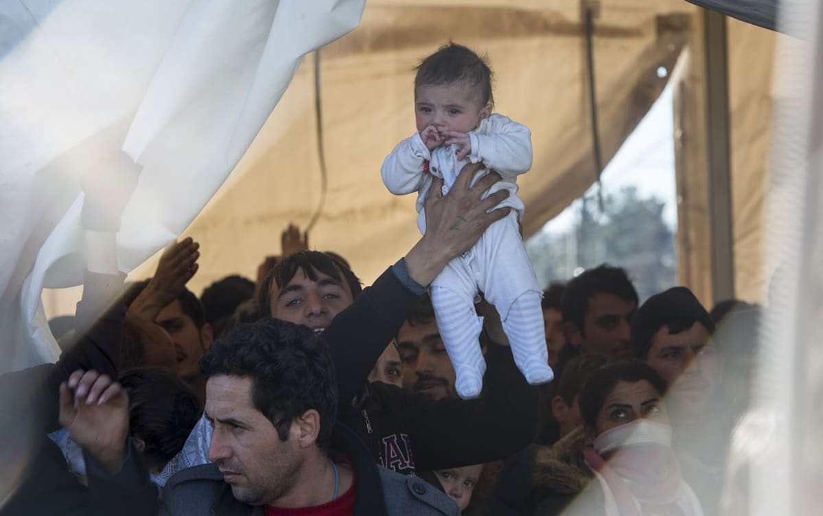 A refugees man lift up his child as he and others await permission to enter Macedonia, near Gevgelia, The Former Yugoslav Republic of Macedonia, 05 March 2016.