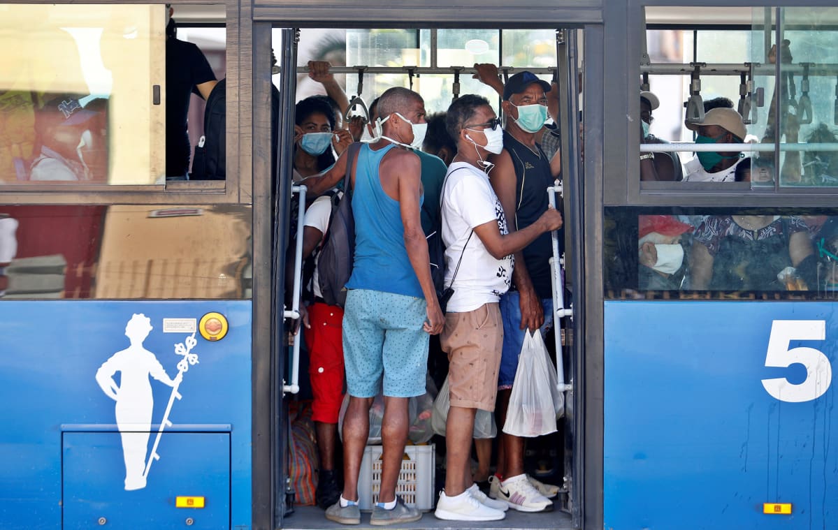Kasvomaskeihin pukeutuneita matkustajia bussin kyydissä.