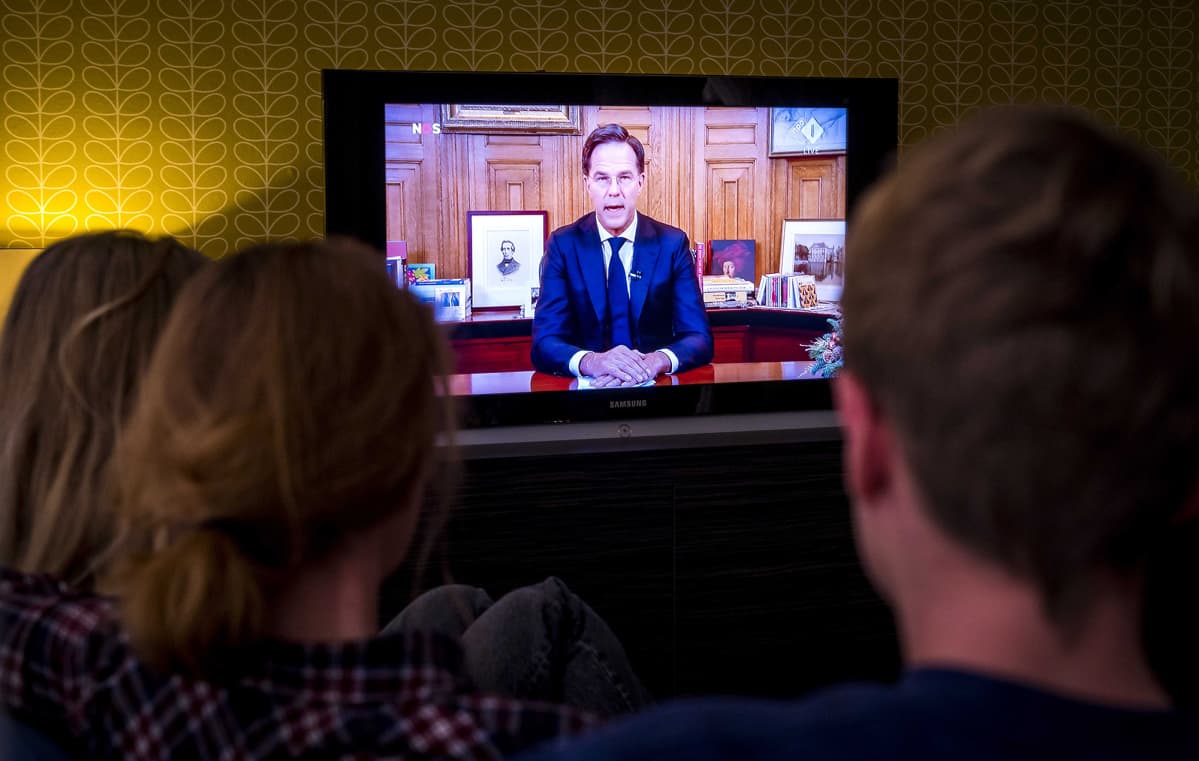 Hollannin pääministeri Mark Rutte puhui televisiossa ja perhe katsoo kotona sohvalta.