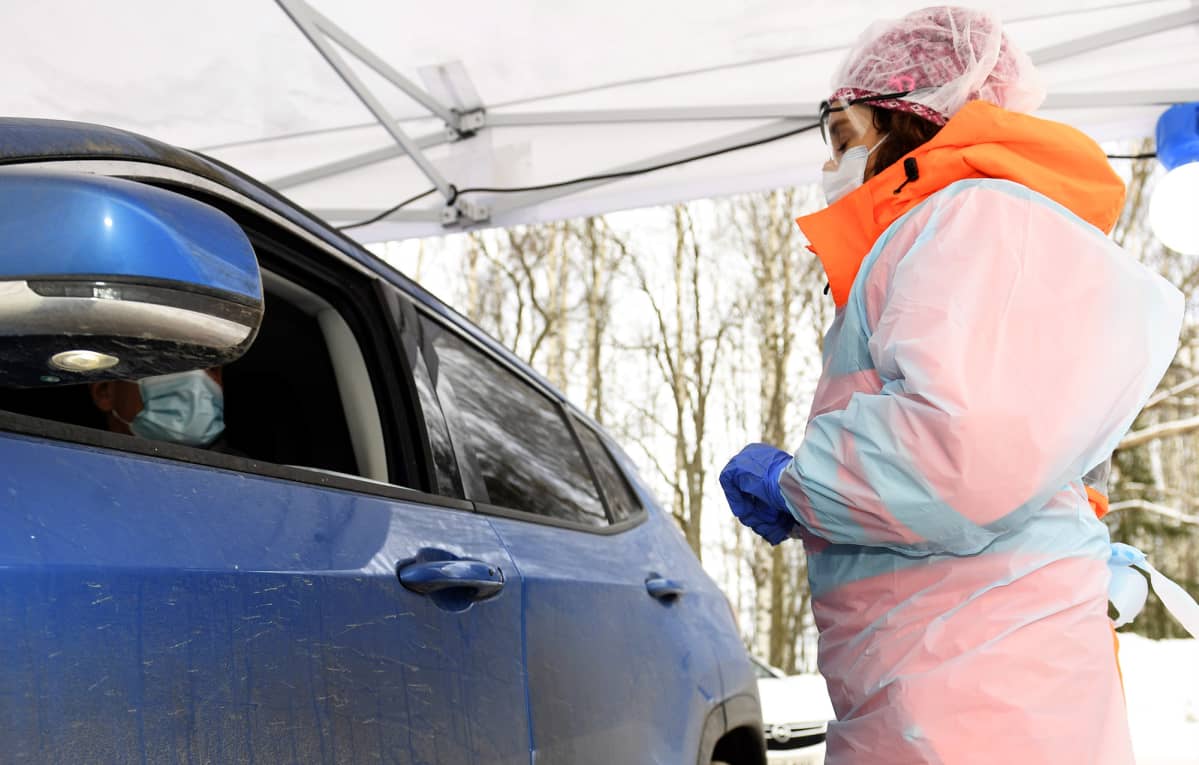 Sairaanhoitaja keskustelee autossa istuvan asiakkaan kanssa koronavirustestin näytteenottopisteellä.