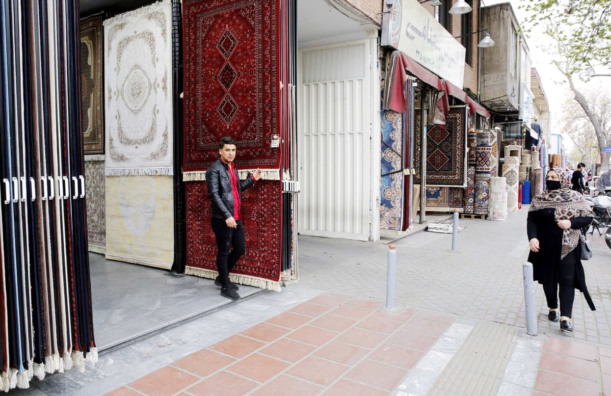 Iranialainen mattokauppias seisoo mattokaupan edustalla Teheranissa.