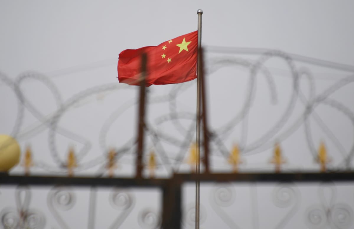 Kuvassa on Kiinan lippu piikkilanka-aidan takana.
