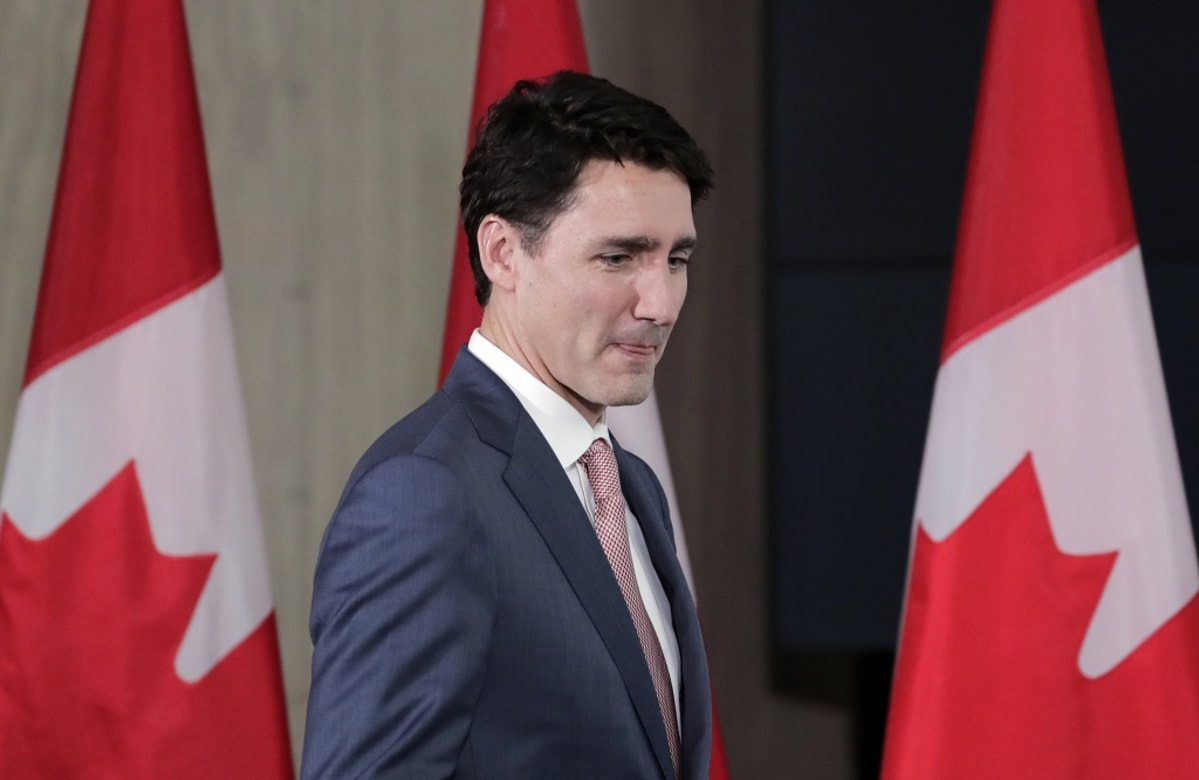 Kuvassa Kanadan pääministeri Justin Trudeau. Hänen takanaan on kolme Kanadan lippua. 