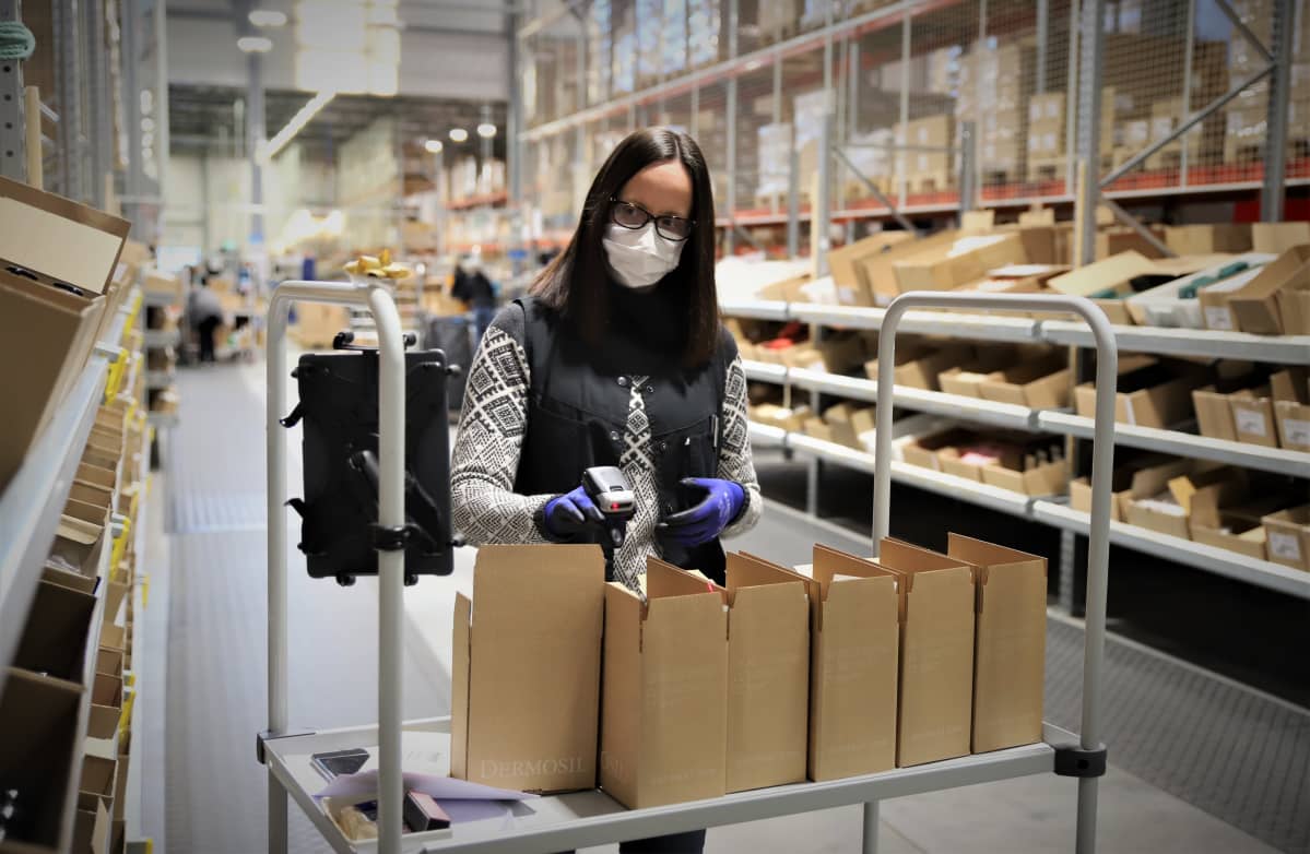 Nainen pakkaa asiakkaan tilaamia tuotteita laatikkoon