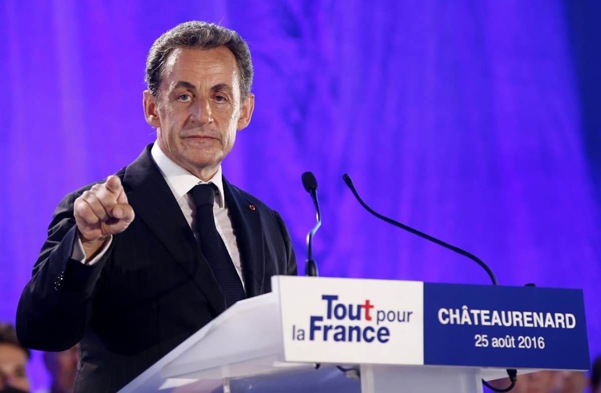Nicolas Sarkozy katsoo suoraan kameraan ja osoittaa sormellaan.